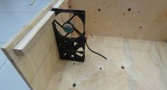 a fan sitting inside of a wooden box on top of plywood planks in an unfinished room
