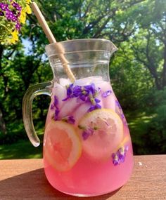 a pitcher filled with ice and lemons on top of a table next to flowers