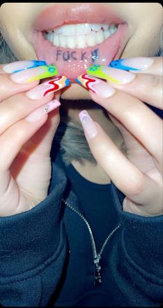 a woman with colorful nails holding up her teeth to show the word fluck on it
