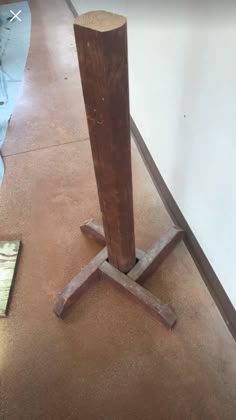 a piece of wood sitting on top of a floor next to a wooden pole in a room