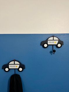 two police cars mounted to the side of a blue wall next to a coat rack