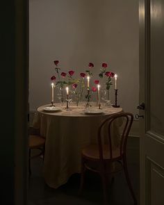 the table is set with candles and roses in vases on top of each other