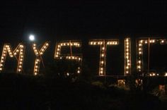 lighted letters that spell out the word my city in front of a building at night