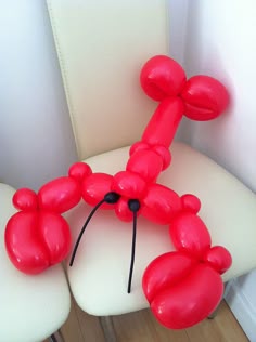 an inflatable balloon dog sitting on top of a white chair next to a wooden floor