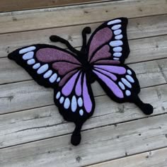 a purple and white butterfly sitting on top of a wooden floor