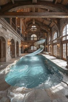 a large indoor swimming pool with a slide in the center and windows on both sides