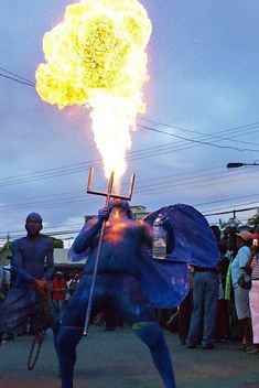 a man in blue and yellow is holding a large object with flames coming out of it