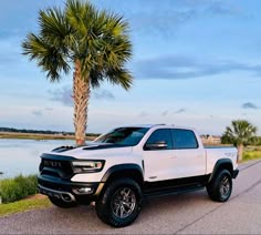 a white truck parked on the side of a road next to a body of water