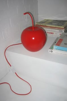 a red apple sitting on top of a white shelf next to books and an mp3 player