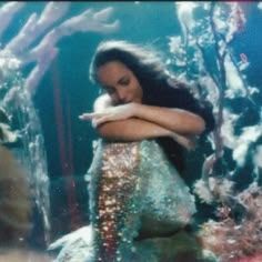 a woman in a mermaid costume is looking at her cell phone while standing under the water