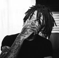 a man with dreadlocks covers his face while holding his hands to his mouth