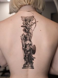 the back of a woman's upper body with an angel and cherub tattoo