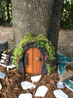 a fairy door in the ground next to a tree