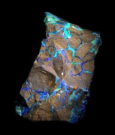 a rock with blue and green lights on it's side, against a black background