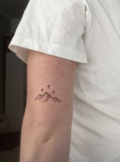 a person with a small tattoo on their arm that has mountains and stars in it