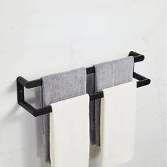 two towels are hanging on the wall in front of a towel rack with two white and gray towels