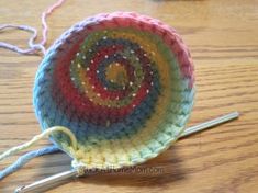 a crocheted dishcloth on a wooden table with knitting needles in front of it