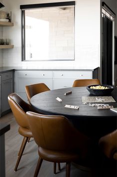 a dining room table with brown chairs and a bowl of food on top of it