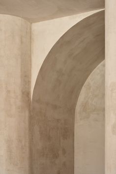 an empty room with white walls and concrete arches on the wall, as well as a bench