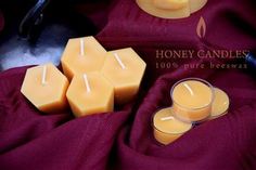 beeswax candles are sitting next to two cups on a purple cloth with the words honey candles