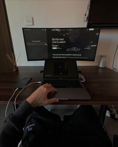 a person sitting at a desk with a laptop computer on their lap and headphones in front of them