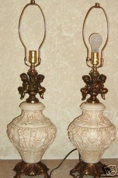 two white vases sitting next to each other on top of a table under a light