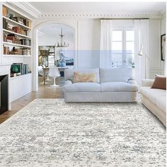 a living room filled with furniture and a white rug on top of a hard wood floor