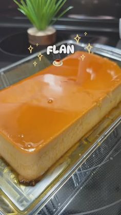 a square cake sitting on top of a plastic tray next to a potted plant
