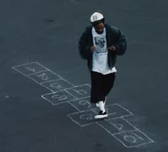 a man standing in the middle of a parking lot with chalk drawings on the ground