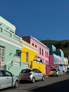 cars parked in front of multi - colored houses on the street