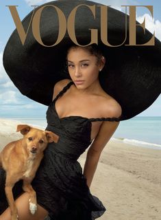 a woman in a black dress and large hat on the beach with a small dog