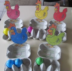an egg carton filled with different colored eggs on top of a table next to cut outs