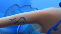 a close up of a person's arm with a tattoo on it and an octopus in the background