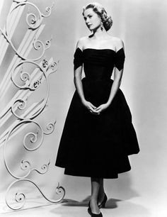 a black and white photo of a woman in a dress with her hands on her hips