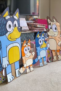 Four large Bluey character boards, setup in a lounge with presents behind.