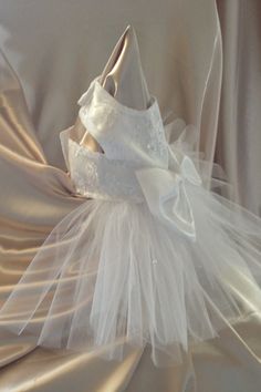 a white dress is sitting on top of a chair with a veil around it's neck