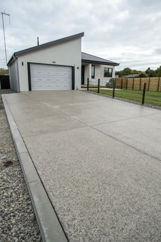 a concrete driveway with gravel in front of it and a garage door on the other side