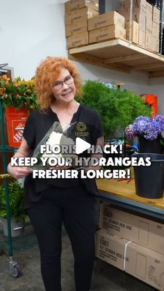 a woman with red hair is standing in front of some plants and flowers on shelves