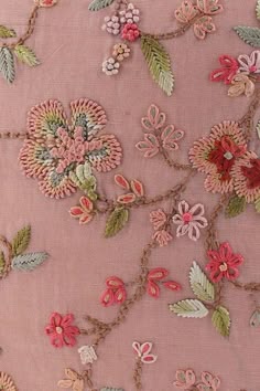 an embroidered pink fabric with flowers and leaves on the side, along with other floral appliques