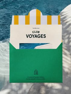 a paper bag with the words club voyages on it sitting in front of a body of water