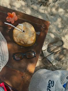a wooden table topped with a pie next to two pairs of sunglasses and a flower