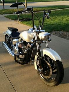 a silver and black motorcycle parked on the side of a road next to a sidewalk