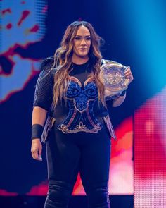 a woman holding a wrestling belt on top of a stage