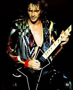 a man with long hair playing an electric guitar