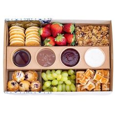a box filled with lots of different types of food next to some grapes and strawberries