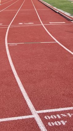 a red track with white lines on it and grass in the backgrouds