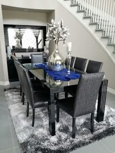 a dining room table with chairs and a vase filled with flowers on top of it