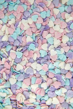 heart shaped candies are scattered on top of each other in blue, pink and white