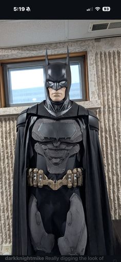a batman costume on display in front of a window with the caption, dark knight really digging the look of