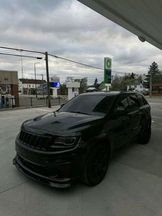 a black jeep is parked in front of a gas station with no one around it